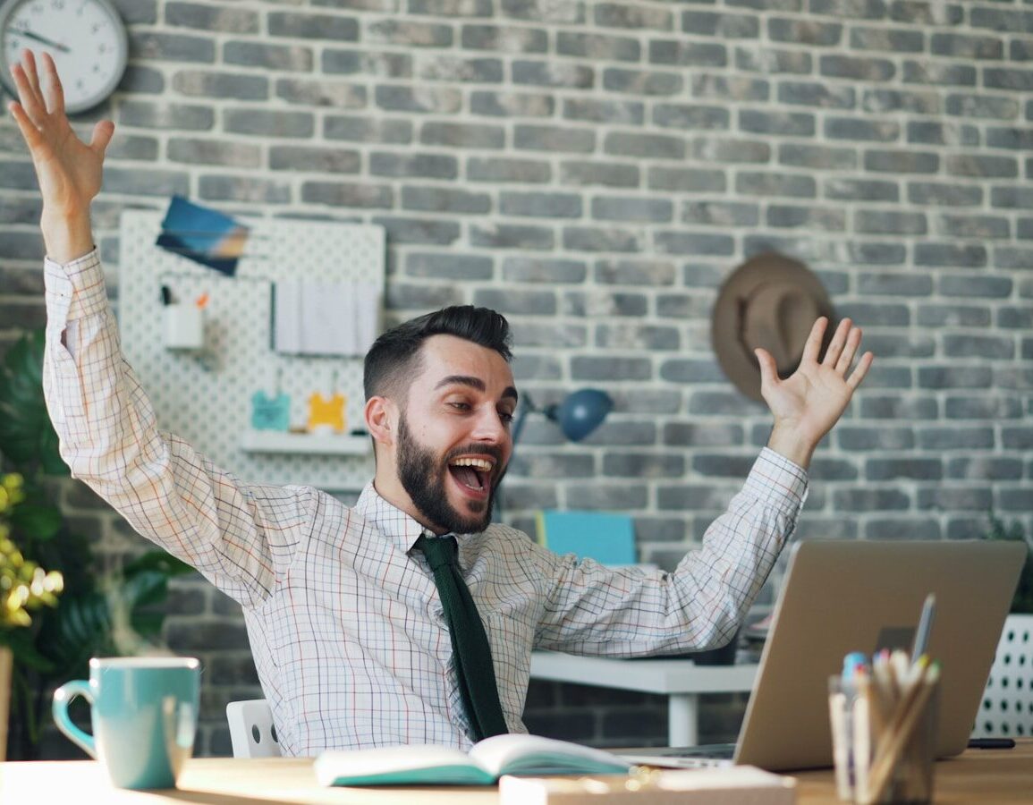 a man sitting at a desk with his arms in the air